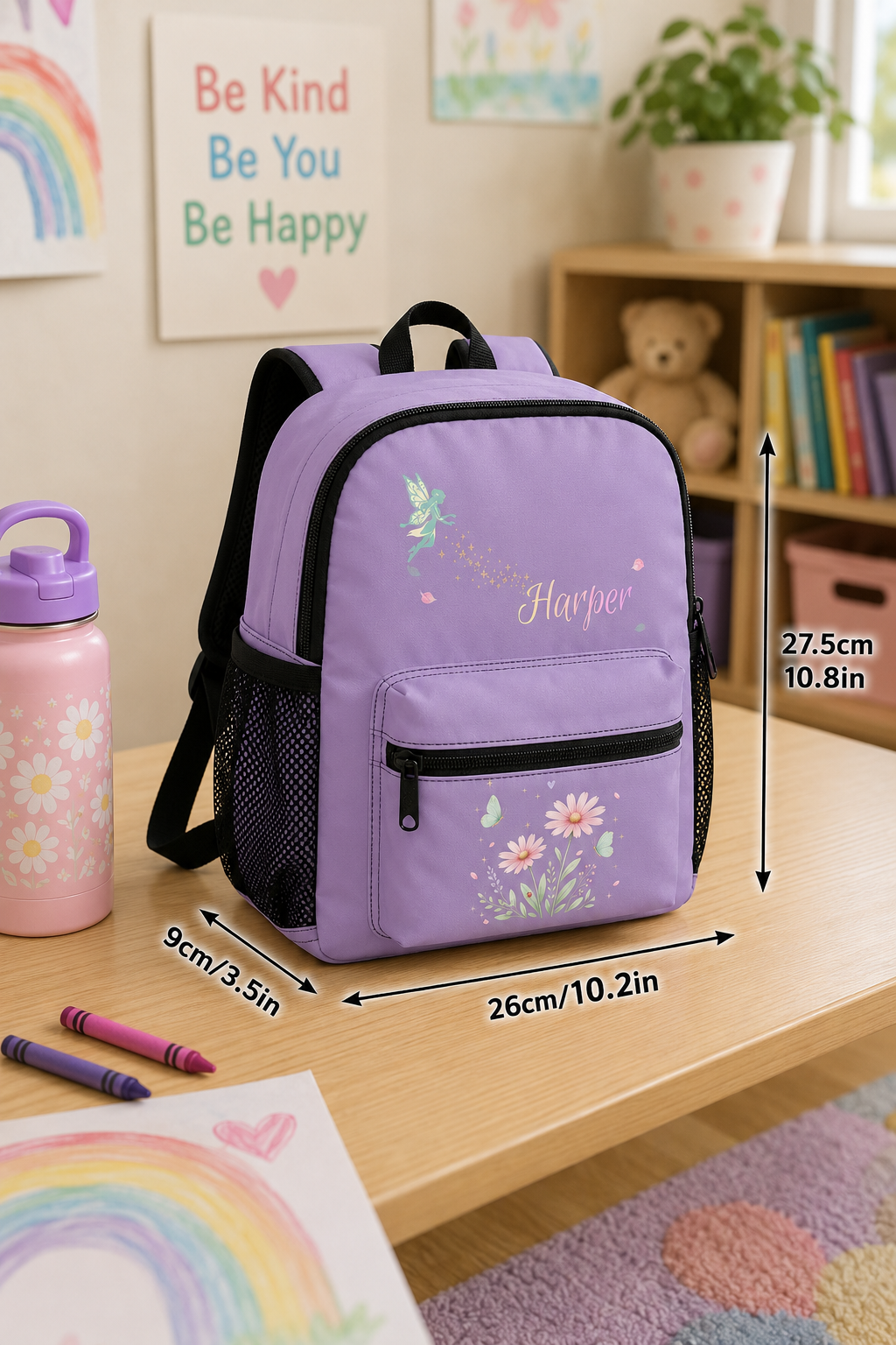 A lavender purple personalized backpack with black mesh side pockets and black straps, decorated with a floral print and the name 'Harper' in script. The backpack is shown on a wooden desk with dimension arrows and text overlays indicating its measurements (27.