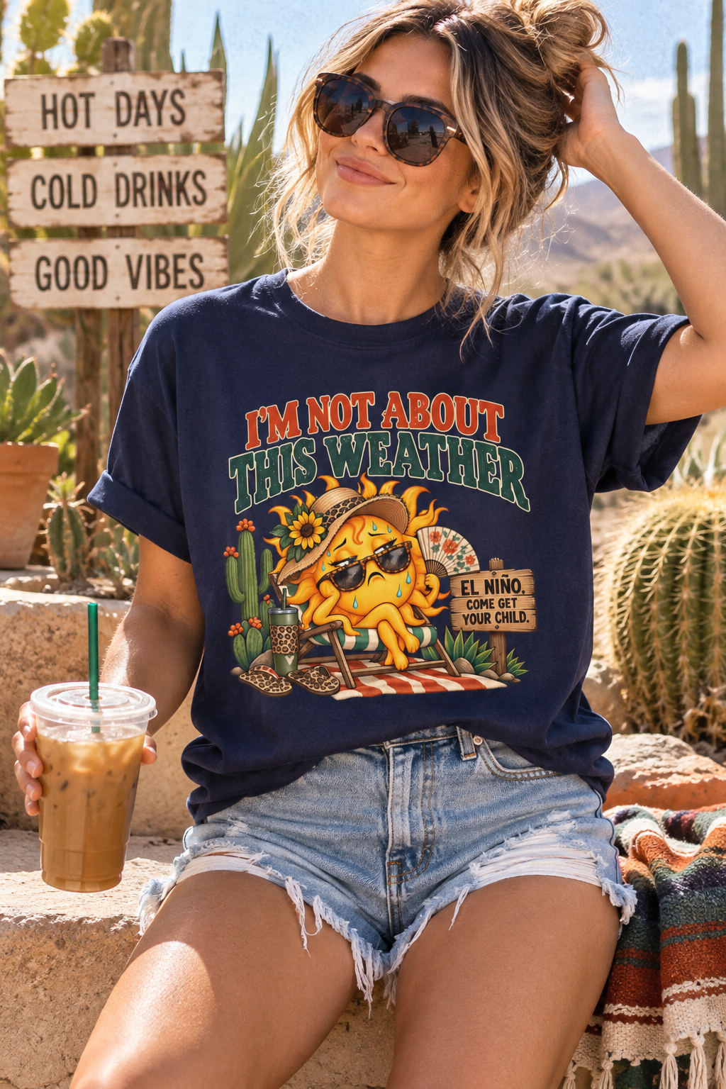 Woman wearing a navy funny El Niño shirt with “I’m Not About This Weather” graphic, sweating sun and cactus design in a hot desert setting.